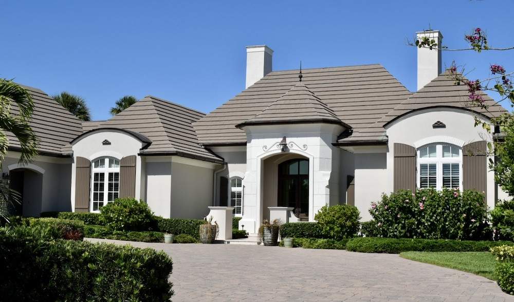 Tan house with brown shutters that have round edges at the top