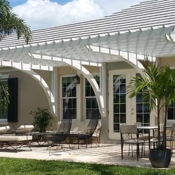 Custom white pergola with arched beams extending from brown house